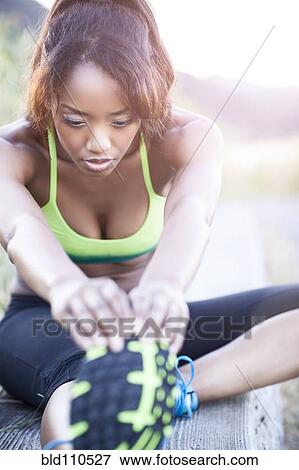 Stock Photo - Mixed race woman stretching in field. Fotosearch