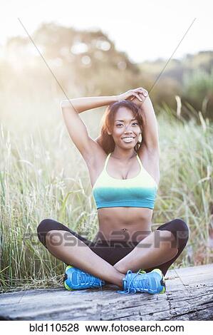 Mixed race woman stretching in field View Large Photo Image Stock Photo - Mixed race woman stretching in field. Fotosearch