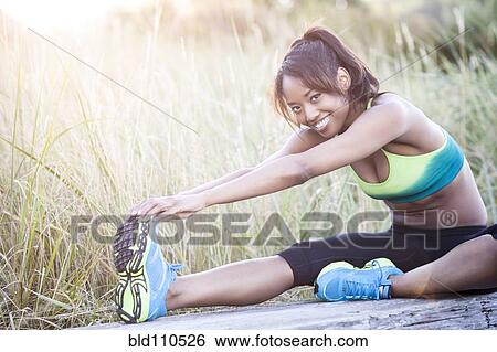 Mixed race woman stretching in field View Large Photo Image Stock Photograph - Mixed race woman stretching in field. Fotosearch