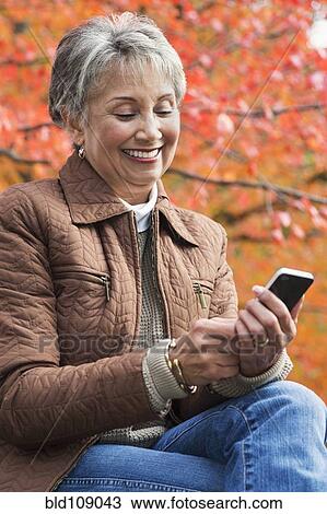 Stock Image - Mixed race woman using cell phone. Fotosearch