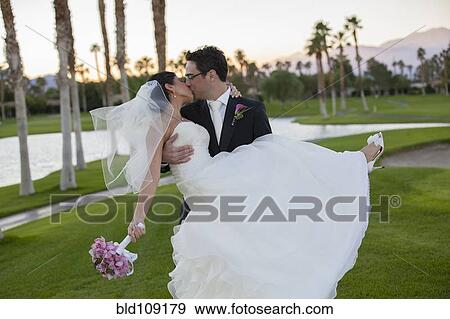 Newlywed couple kissing on golf course View Large Photo Image Stock Photo - Newlywed couple kissing on golf course. Fotosearch