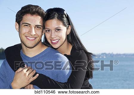 Smiling mixed race couple hugging by water View Large Photo Image Stock Photograph - Smiling mixed race couple hugging by water. Fotosearch