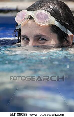 Stock Photo - Woman in goggles peeking up from pool. Fotosearch