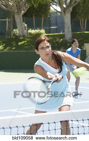 Stock Photo - Woman playing tennis on court. Fotosearch