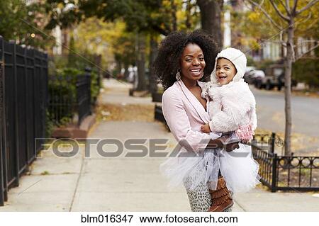 Black mother carrying daughter on city street View Large Photo Image Stock Photo - Black mother carrying daughter on city street. Fotosearch