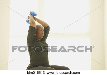 Stock Image - Black woman lifting weights. Fotosearch