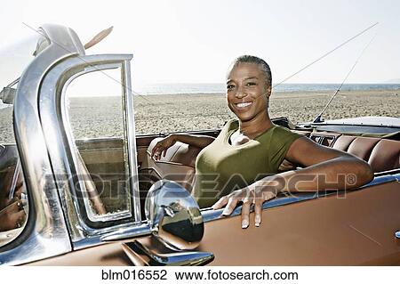 Stock Image - Black woman sitting in convertible. Fotosearch