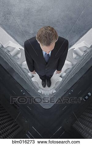 Stock Image - Caucasian businessman on skyscraper ledge. Fotosearch