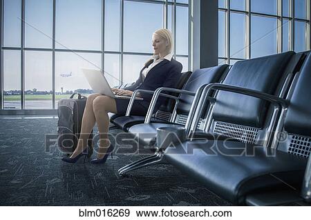 Stock Photo - Caucasian businesswoman using laptop in airport. Fotosearch