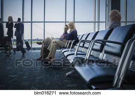 Stock Image - Caucasian couple using digital tablet in airport. Fotosearch