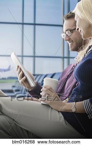 Stock Photo - Caucasian couple using digital tablet in airport. Fotosearch