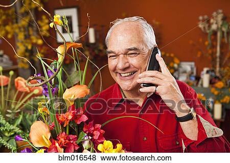 Stock Photo - Caucasian florist talking on phone in shop. Fotosearch