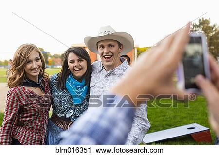 Stock Image - Caucasian friends taking pictures together. Fotosearch
