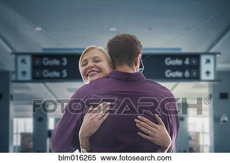 Stock Photography - Caucasian hugging in airport. Fotosearch