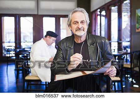 Stock Photo - Caucasian man holding menu in restaurant. Fotosearch