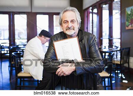 Caucasian man holding menu in restaurant View Large Photo Image Stock Photo - Caucasian man holding menu in restaurant. Fotosearch