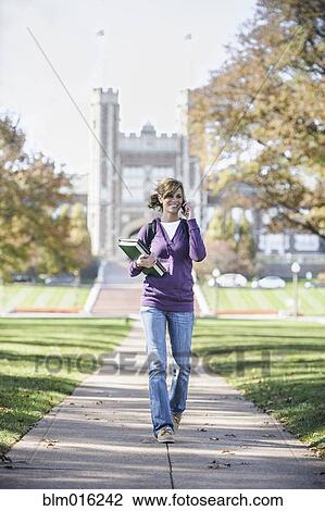 Stock Image - Caucasian student on cell phone on campus. Fotosearch