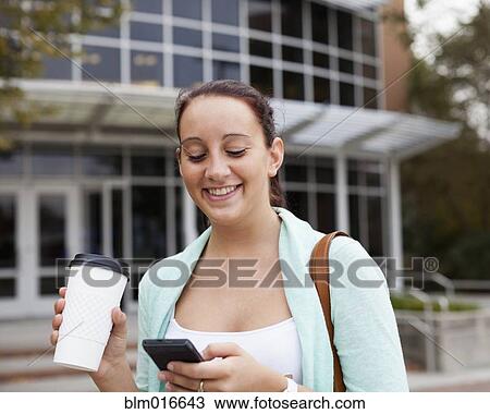 Stock Image - Caucasian student using cell phone on campus. Fotosearch
