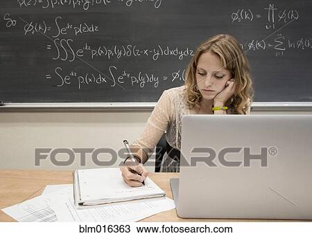Stock Image - Caucasian student using laptop in classroom. Fotosearch