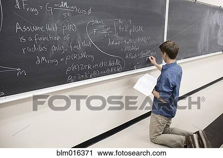 Stock Image - Caucasian student writing on blackboard. Fotosearch