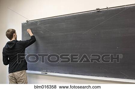 Stock Photo - Caucasian student writing on blackboard. Fotosearch