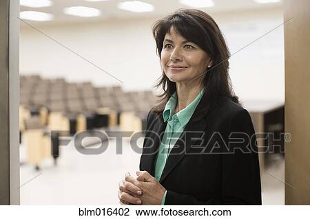 Stock Image - Caucasian teacher in empty classroom. Fotosearch