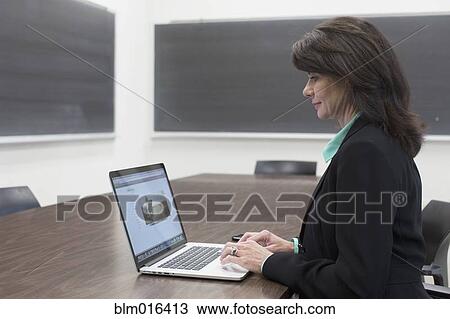 Caucasian teacher using laptop in classroom View Large Photo Image Stock Image - Caucasian teacher using laptop in classroom. Fotosearch