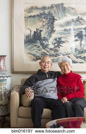 Stock Photo - Chinese couple sitting on sofa. Fotosearch