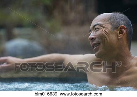 Stock Photo - Chinese man relaxing in hot tub. Fotosearch