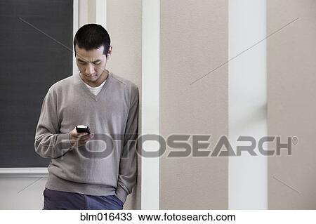 Chinese man using cell phone in hallway View Large Photo Image Stock Image - Chinese man using cell phone in hallway. Fotosearch