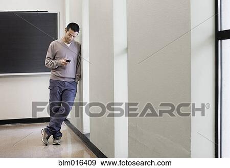 Stock Photo - Chinese man using cell phone in hallway. Fotosearch