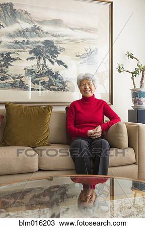 Stock Image - Chinese woman sitting on sofa. Fotosearch