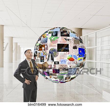 Stock Photo - Hispanic businessman examining illustration of globe. Fotosearch