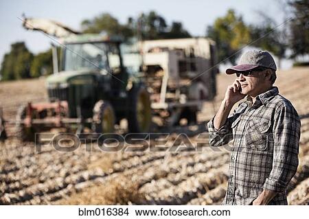 Hispanic farmer on cell phone in crop field View Large Photo Image Picture - Hispanic farmer on cell phone in crop field. Fotosearch