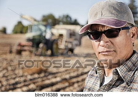 Hispanic farmer standing by harvester View Large Photo Image Stock Photo - Hispanic farmer standing by harvester. Fotosearch