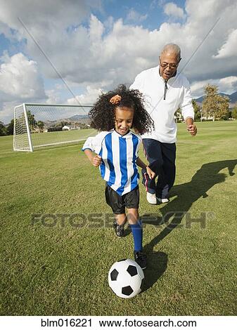 Stock Image - Man playing soccer with granddaughter. Fotosearch