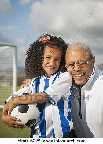 Stock Photography - Man smiling with granddaughter on soccer field. Fotosearch