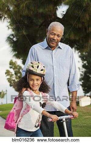 Stock Photograph - Man standing with granddaughter outdoors. Fotosearch
