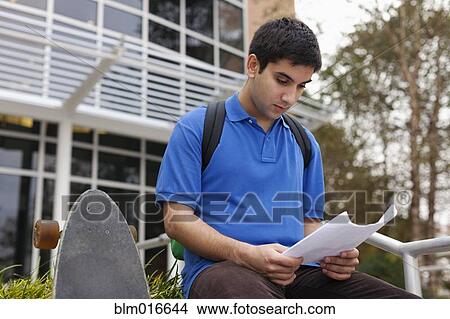 Picture - Middle Eastern student reading notes on campus. Fotosearch