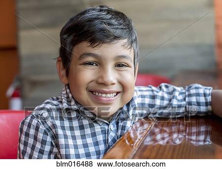 Stock Photo - Mixed race boy sitting in restaurant. Fotosearch