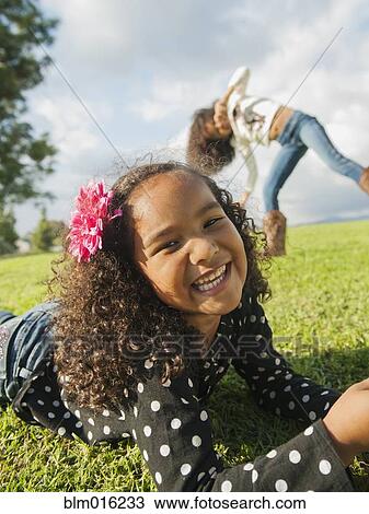 Stock Image - Mixed race girl laying in grass. Fotosearch