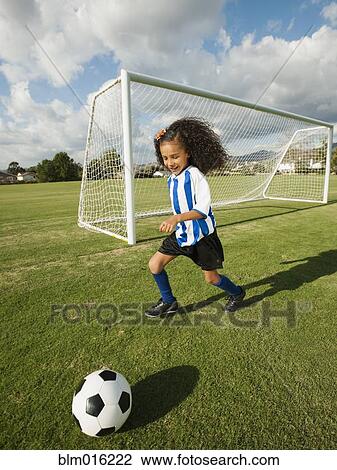 Stock Image - Mixed race girl playing soccer. Fotosearch