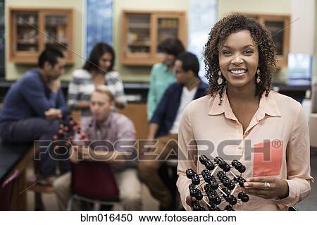 Stock Image - Mixed race student holding molecular model in lab classroom. Fotosearch