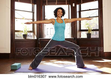Mixed race woman practicing yoga in living room View Large Photo Image Stock Photo - Mixed race woman practicing yoga in living room. Fotosearch
