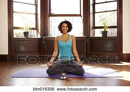 Stock Photograph - Mixed race woman practicing yoga in living room. Fotosearch