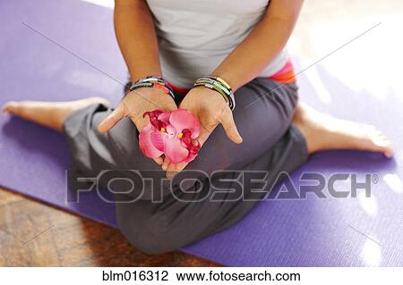 Stock Image - Mixed race woman with flowers on yoga mat. Fotosearch