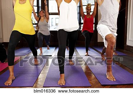Stock Photograph - People practicing yoga in class. Fotosearch