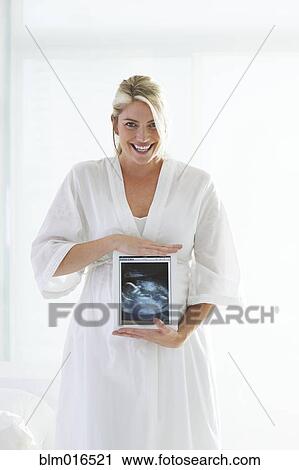 Pregnant Caucasian woman holding sonogram picture View Large Photo Image Stock Image - Pregnant Caucasian woman holding sonogram picture. Fotosearch