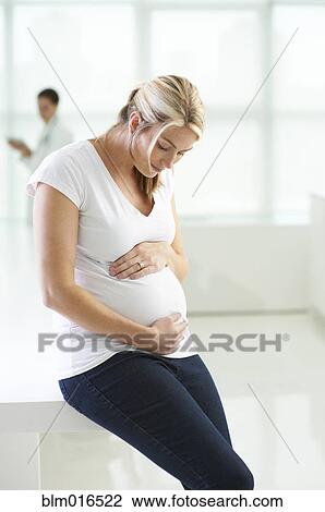 Stock Image - Pregnant Caucasian woman holding stomach. Fotosearch
