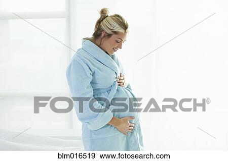 Stock Photo - Pregnant Caucasian woman holding stomach. Fotosearch